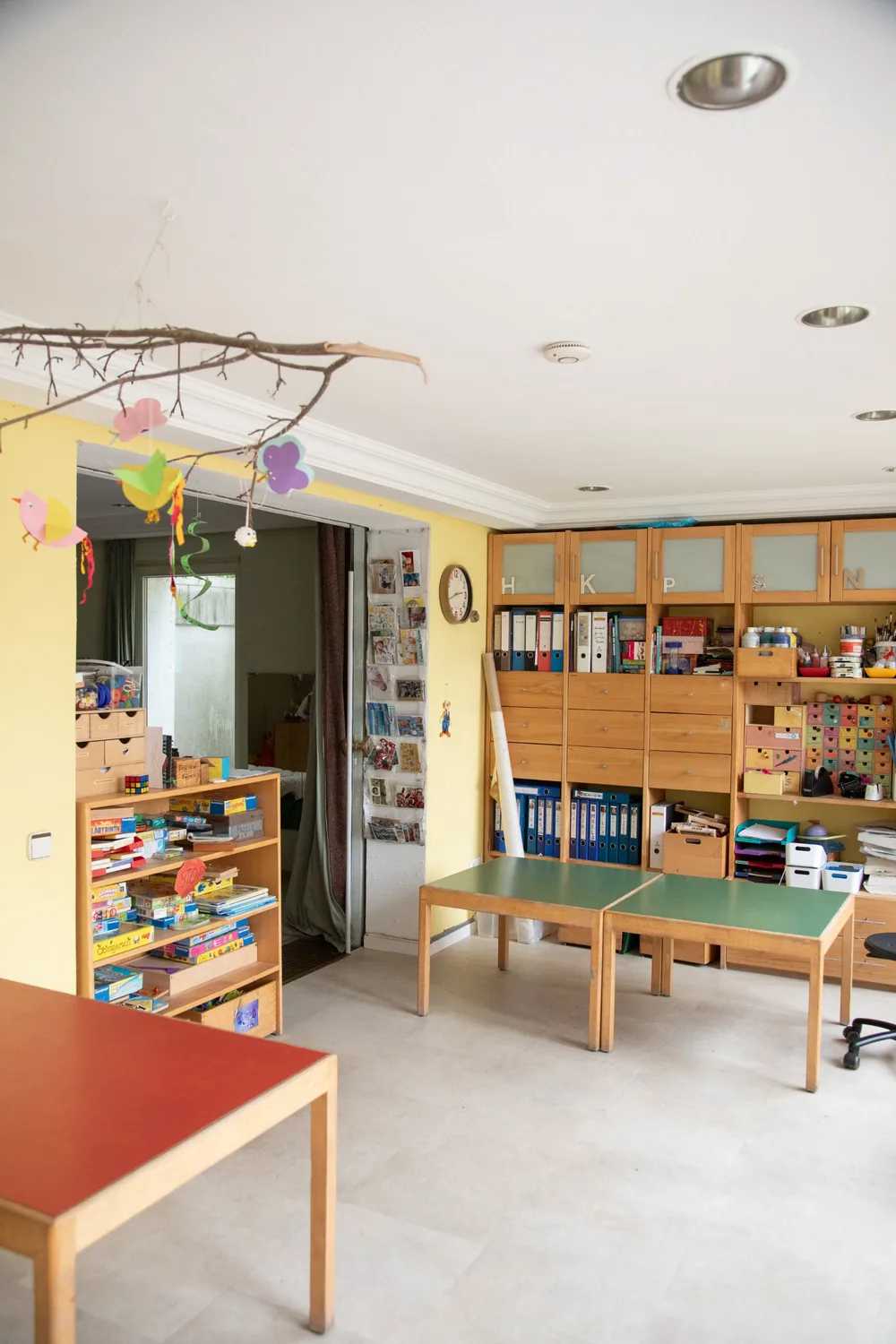 Gruppenraum der Kita Kinderwerkstatt mit Holzregalen, Basteltischen und Kinderstühlen