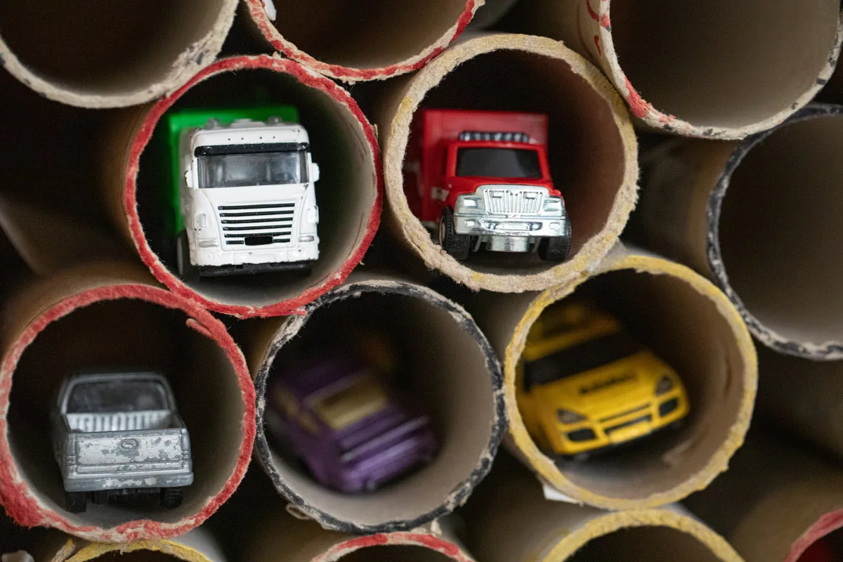 Spielzeugautos und Lastwagen, in Papprollen einsortiert – Spielmaterial in der Kinderwerkstatt